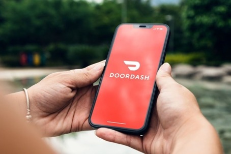 Close-up view of hands holding a smartphone displaying the DoorDash app.