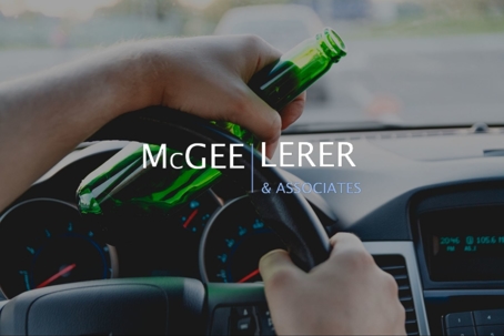 man holds a steering wheel and beer bottle