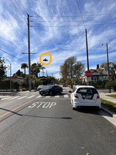 Two cars waiting at a stop sign.