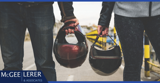 motorcyclists holding helmets