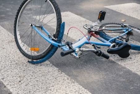 A bicycle lies on a crosswalk after an accident.
