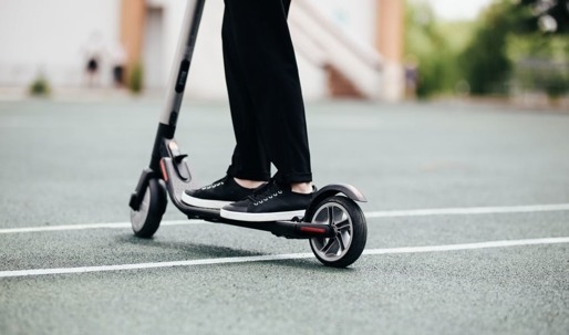 A person stands on an electric scooter.
