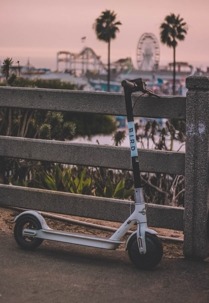 A Bird scooter is parked by a fence
